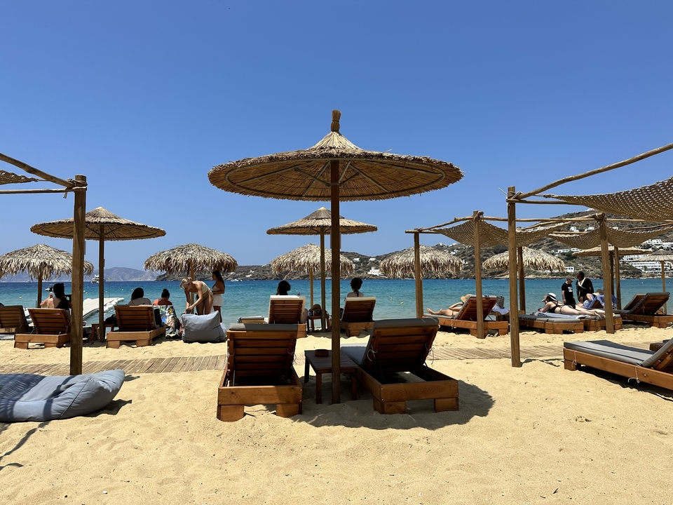 People enjoying a sunny day at the beach with umbrellas and sunbeds.