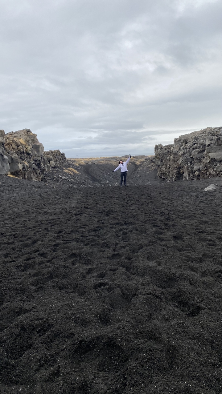 Volcanic black sand beach with a person celebrating