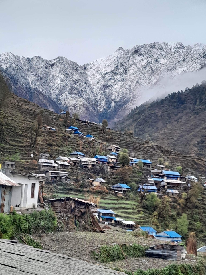 Village in the mountains with blue rooftops and terraced fields.