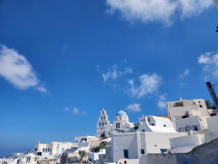 Whitewashed buildings with blue domes under a clear blue sky.