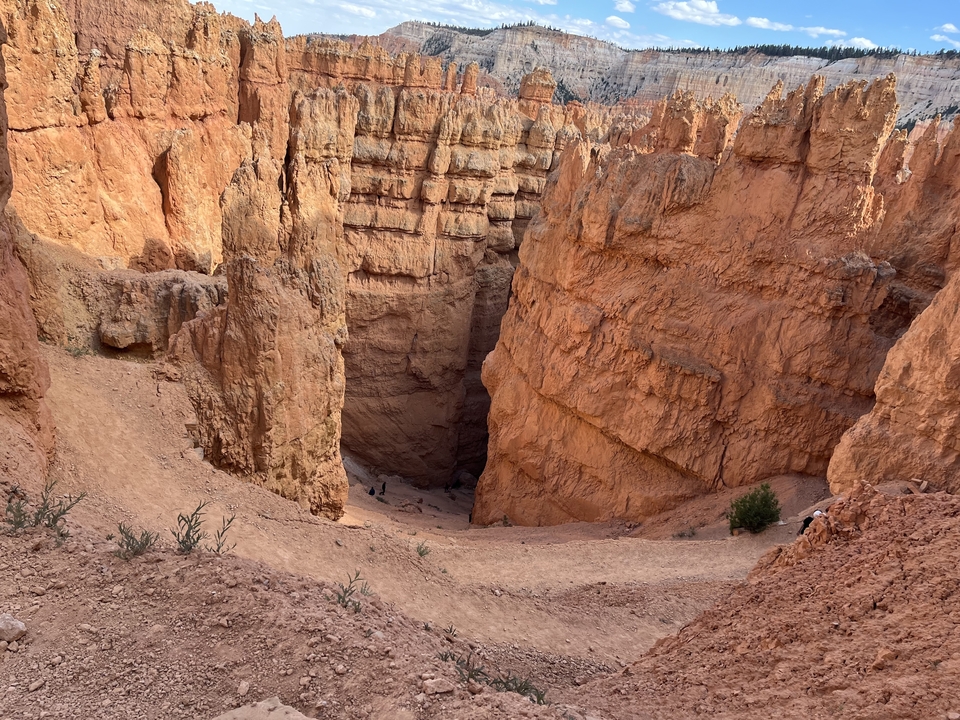 Narrow canyon path with orange rock walls.