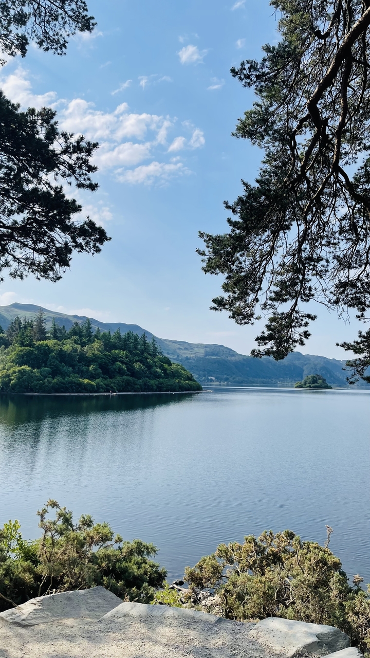 Lac pittoresque aux rives bordées d'arbres et aux collines lointaines.