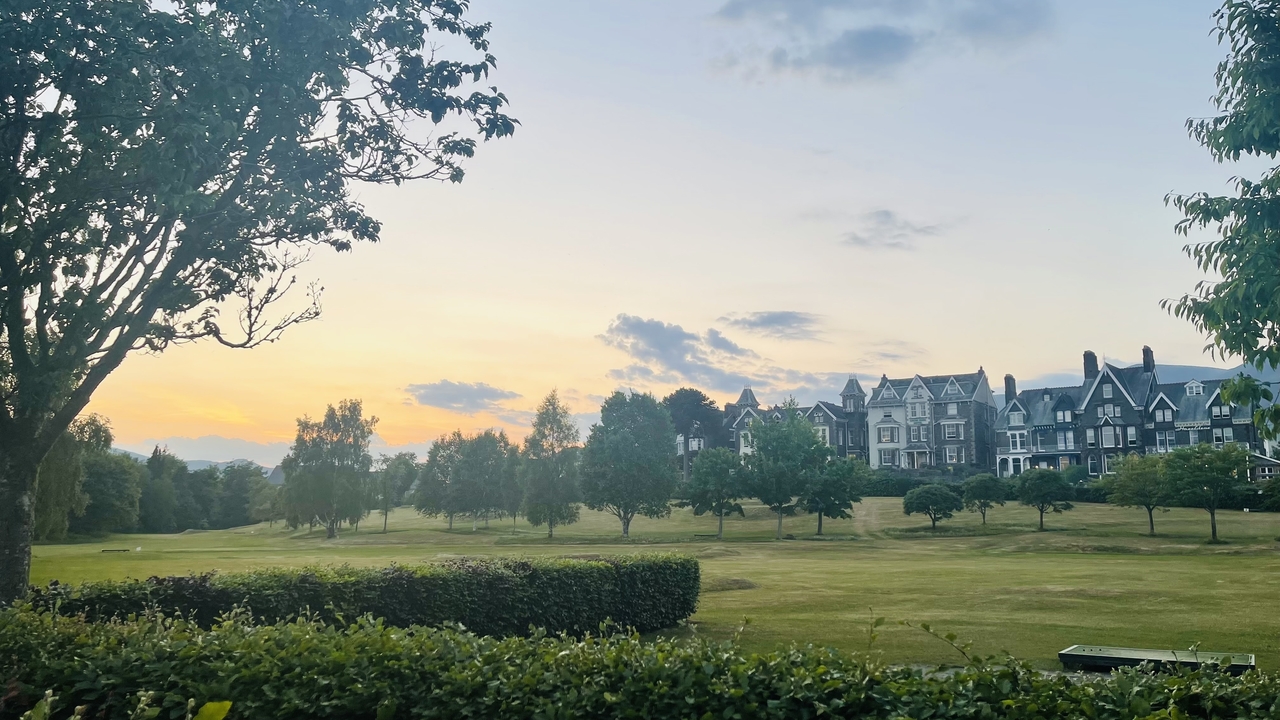 Vue au coucher du soleil d'un grand bâtiment avec vue sur le jardin.