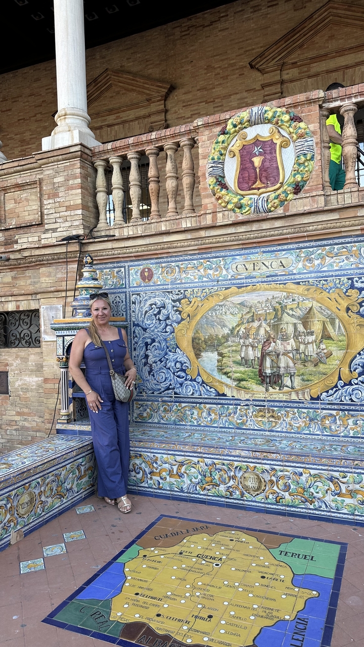 A woman standing next to a decorative mural.