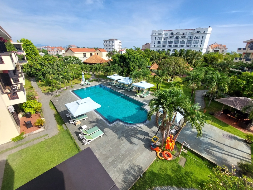 Aerial view of a large swimming pool in a resort setting with trees.