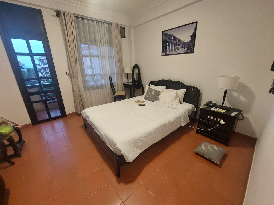 Simple hotel room with a bed and small balcony.