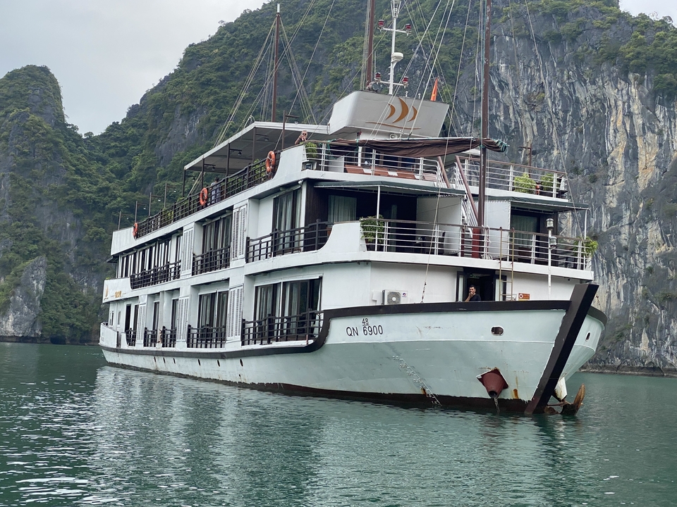 Large cruise ship in Halong Bay, Vietnam, with misty hills in the background.