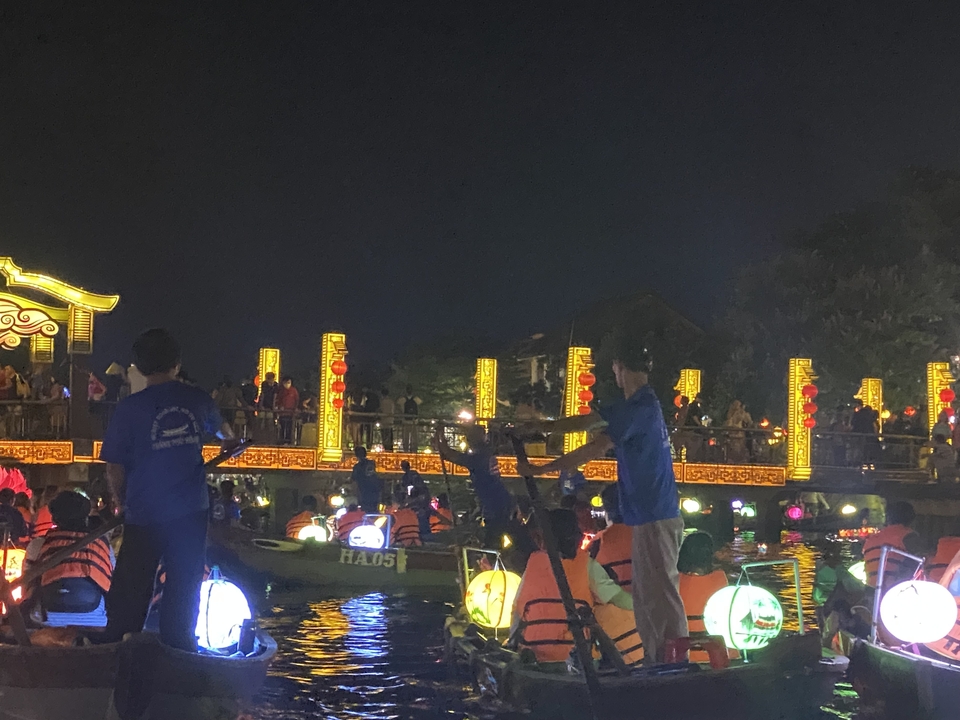 Night scene with boats and colorful lights reflecting on water, Hoi An, Vietnam.
