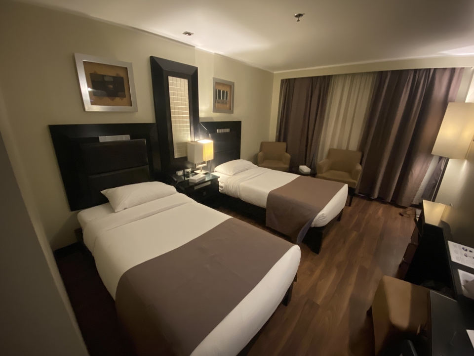 Hotel room with two beds and warm lighting.