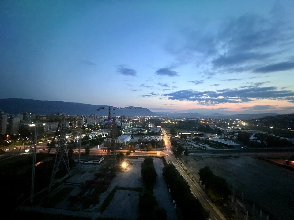 Cityscape view during twilight with a crane and buildings visible.