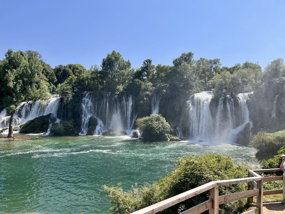Waterfall with lush greenery in bright daylight.