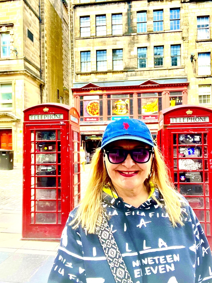 Woman standing between two traditional telephone boxes.