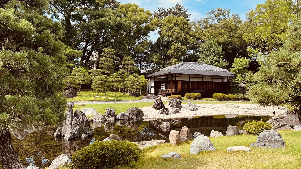 Japanese garden with traditional house and pond.
