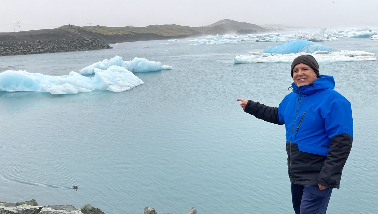 Person pointing at icebergs in a glacier lagoon.