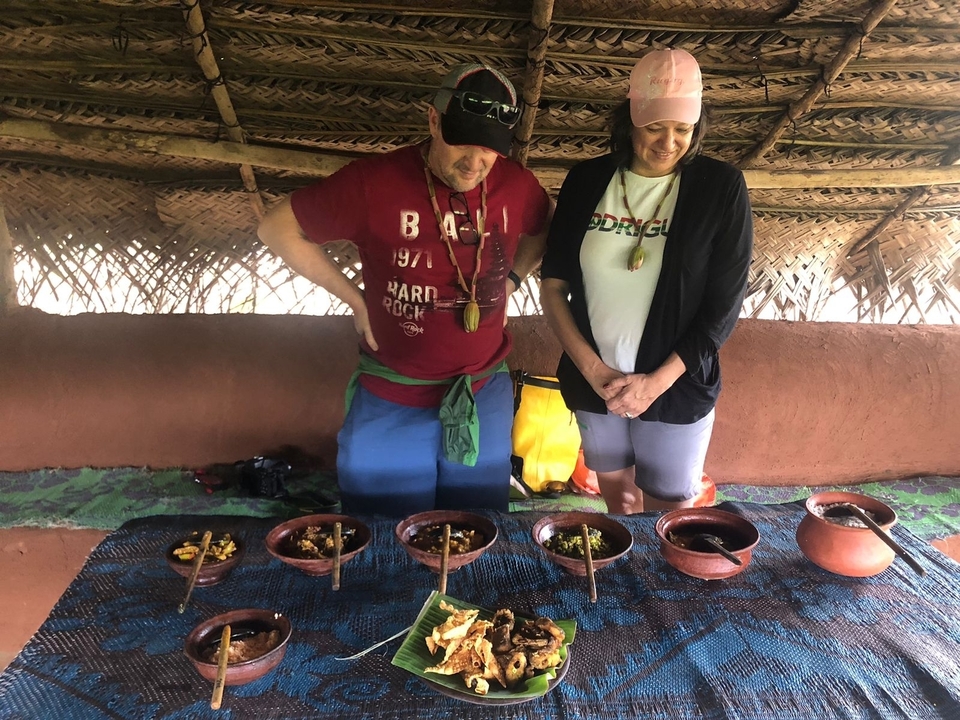 Two people observing dishes inside a hut.