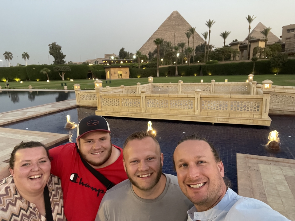 Group selfie with people and pyramids in the background.