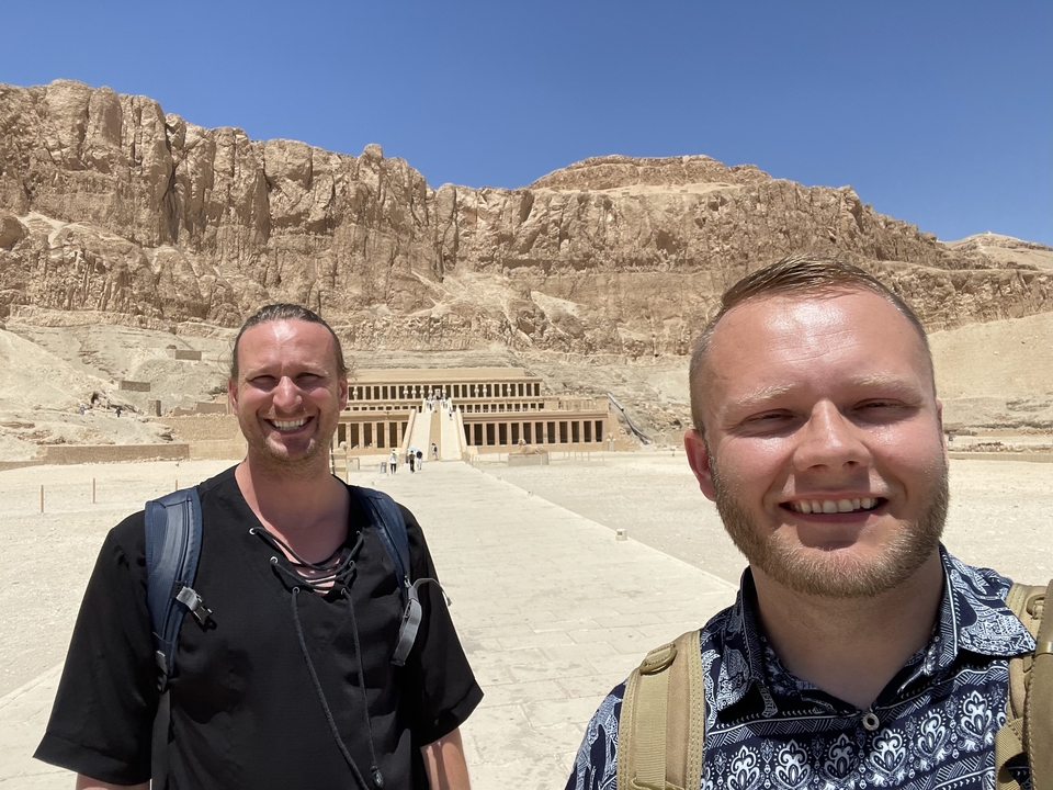 Two men posing in front of a large temple.