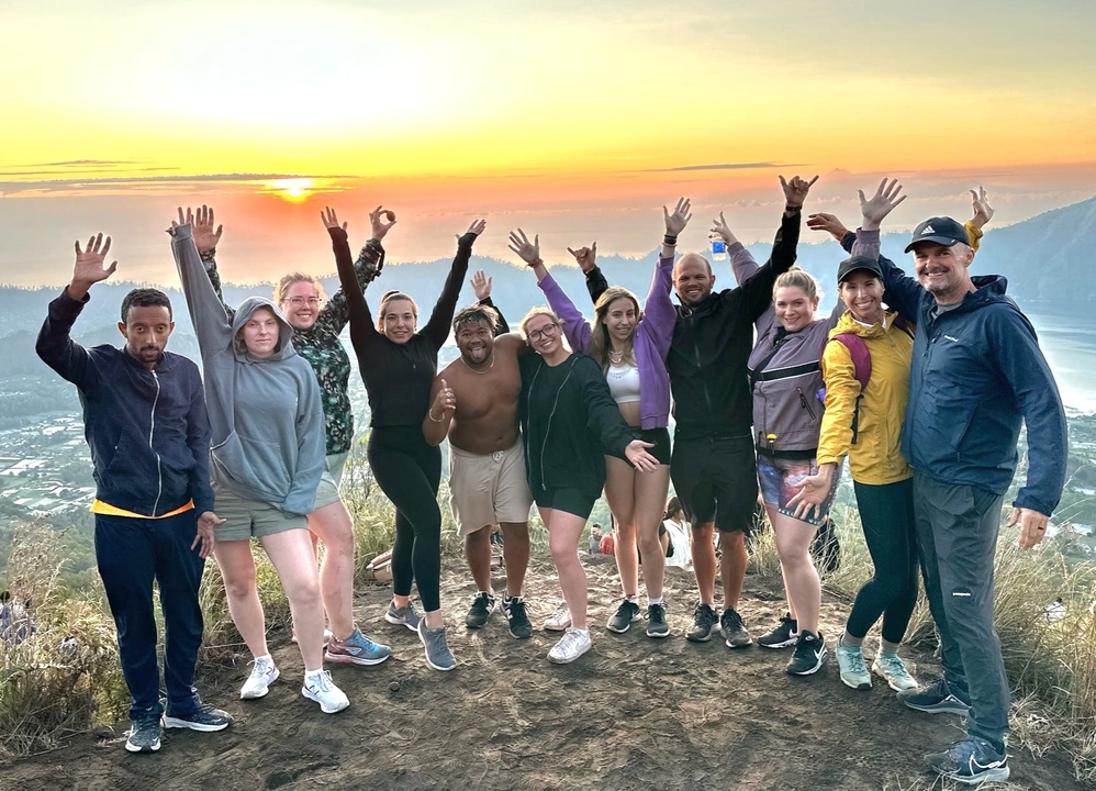 Group at sunrise with scenic view and joyful expression.