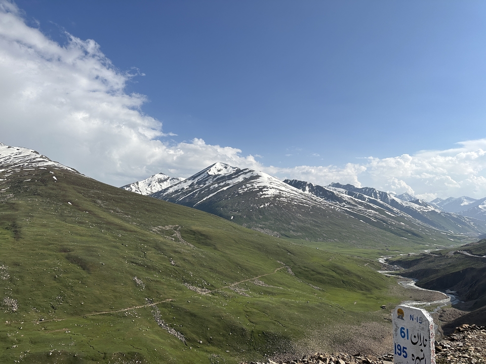 Snow-capped mountains and green valleys under blue skies.