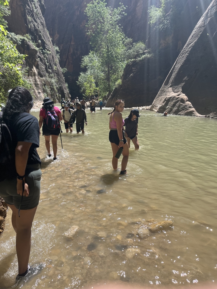Group of people wading through a shallow river