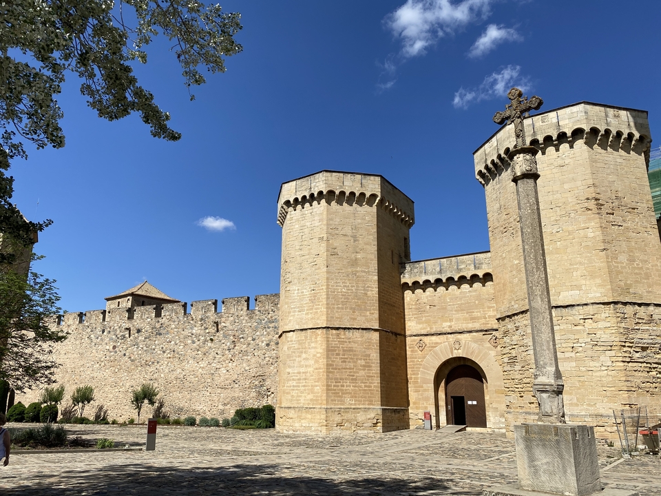 Castle with towers and wall under a bright blue sky.