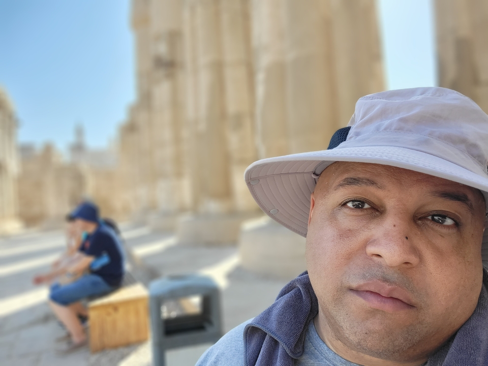 Gros plan d'une personne avec des colonnes antiques en arrière-plan.