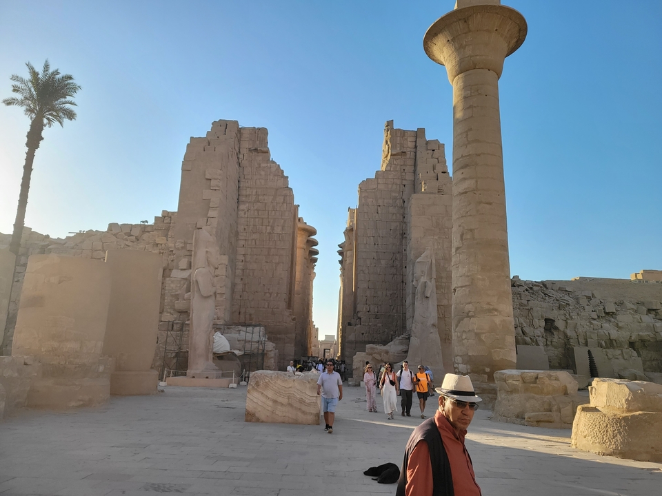 Ruines de temple avec de hautes colonnes et des gens qui marchent.