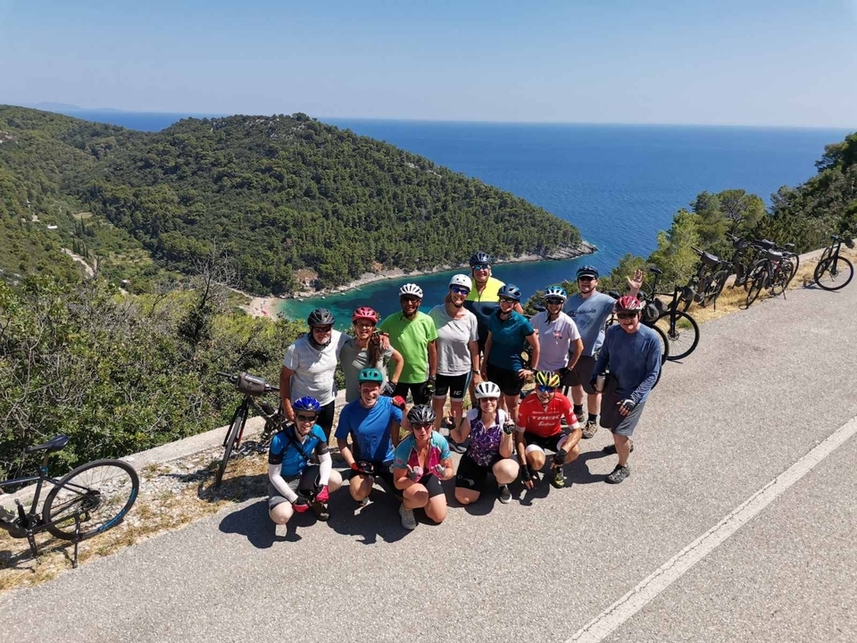 Groupe de cyclistes posant sur une route avec des arbres et une vue sur la mer.