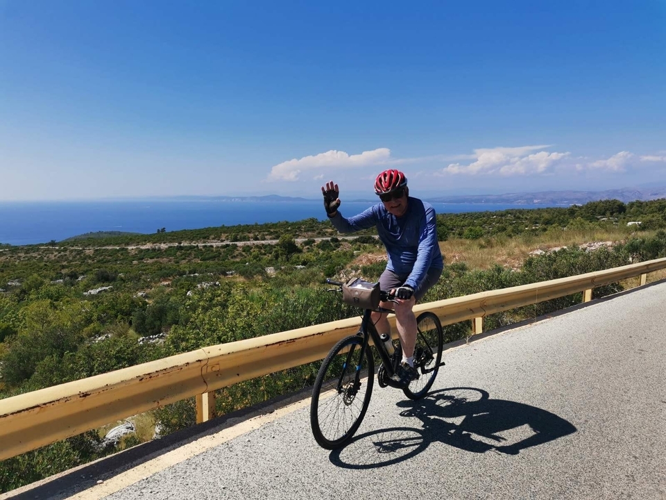 Cycliste sur une route avec la mer en arrière-plan.