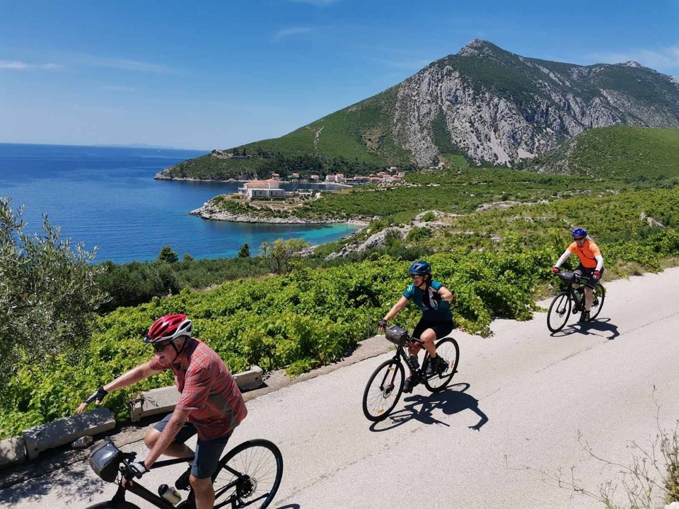 Cyclistes roulant sur une route côtière avec vue sur la mer.
