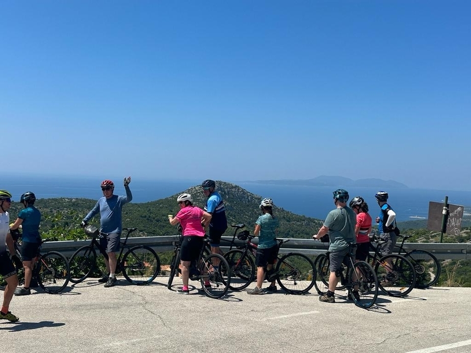Groupe de cyclistes sur une route surplombant la mer.