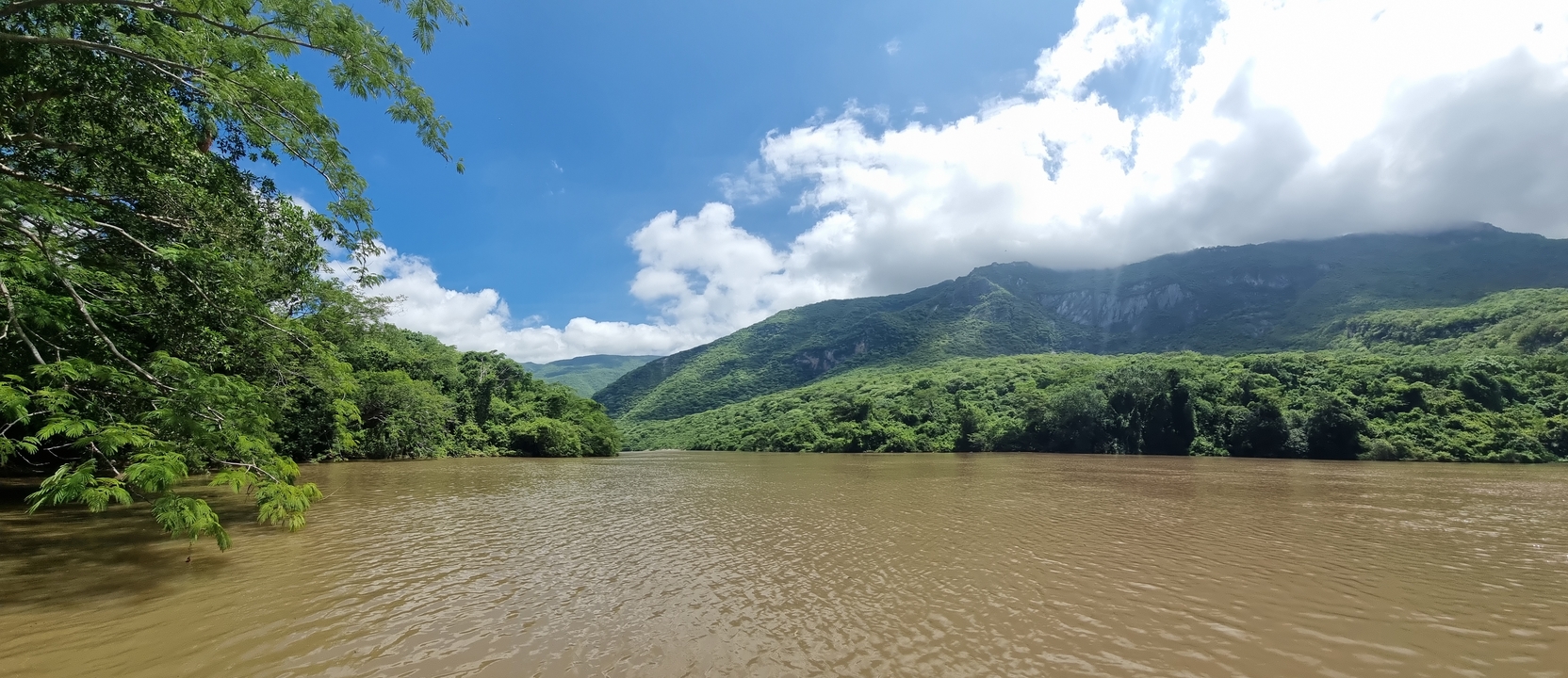 Brown river with green hills in the background.