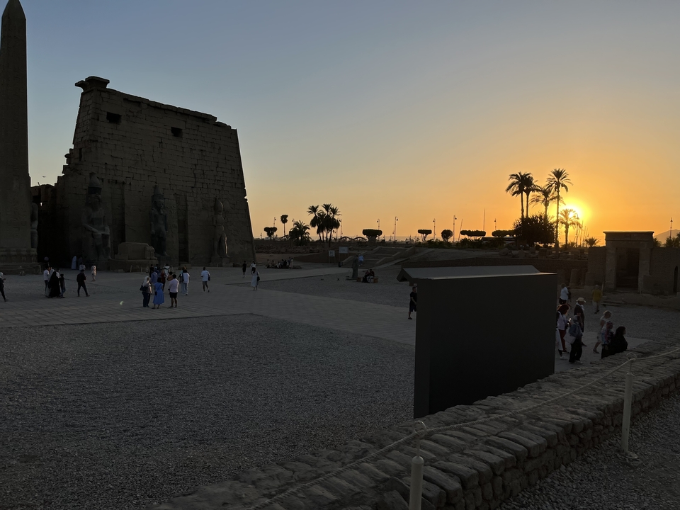 Sunset view of an ancient temple with people exploring.