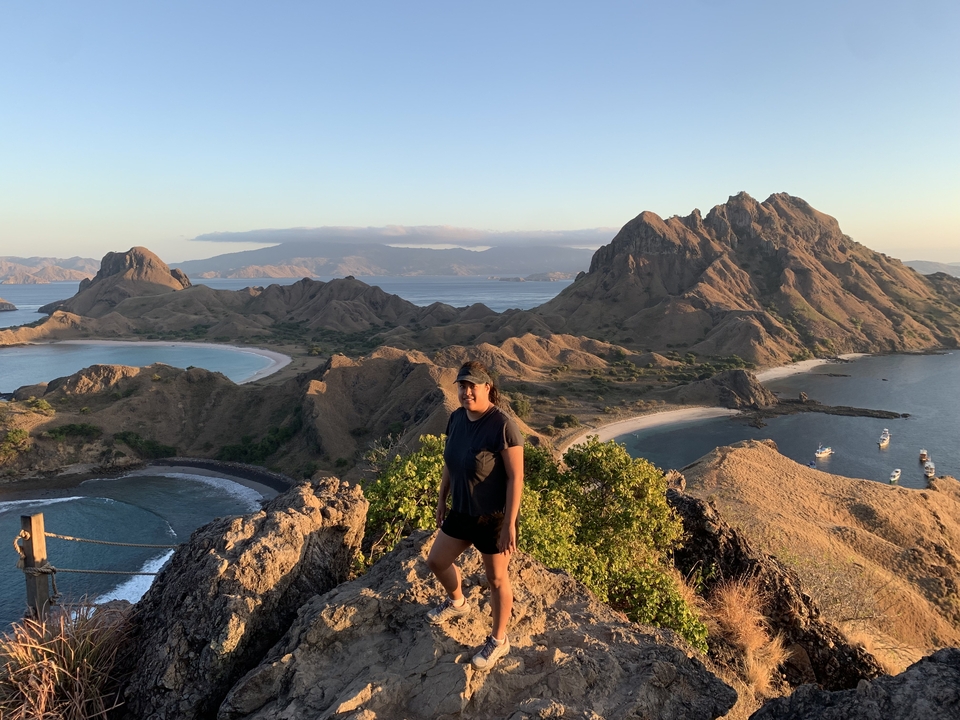 A person standing on a hill with dramatic coastal landscapes and islands.