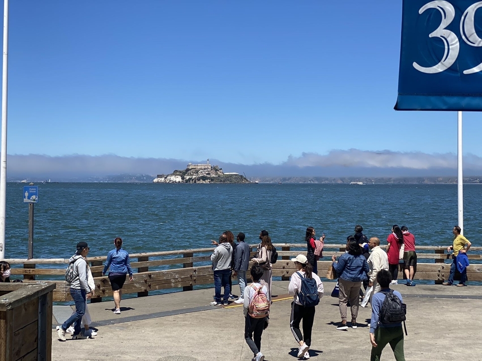 Des gens sur une jetée regardent une île de l'autre côté de l'eau.