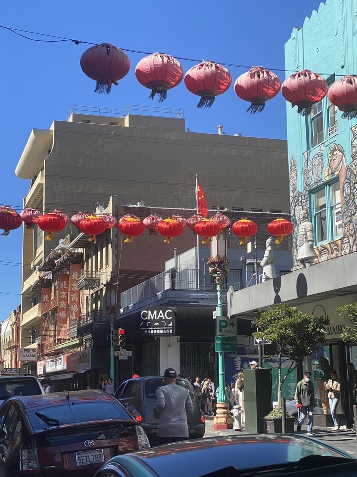 Une scène de rue urbaine avec des lanternes rouges suspendues entre les bâtiments.