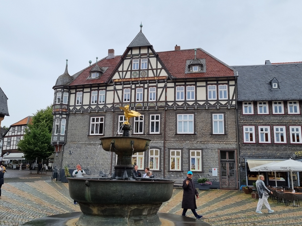 Une place de ville animée avec des bâtiments à colombages et une fontaine.