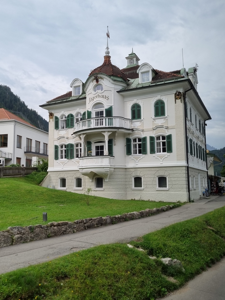 Un bâtiment historique blanc avec des volets verts et une architecture complexe.