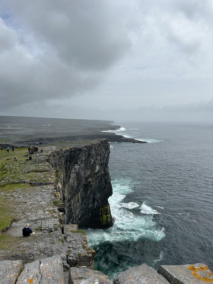 Falaises surplombant l'océan avec des personnes marchant le long du bord.