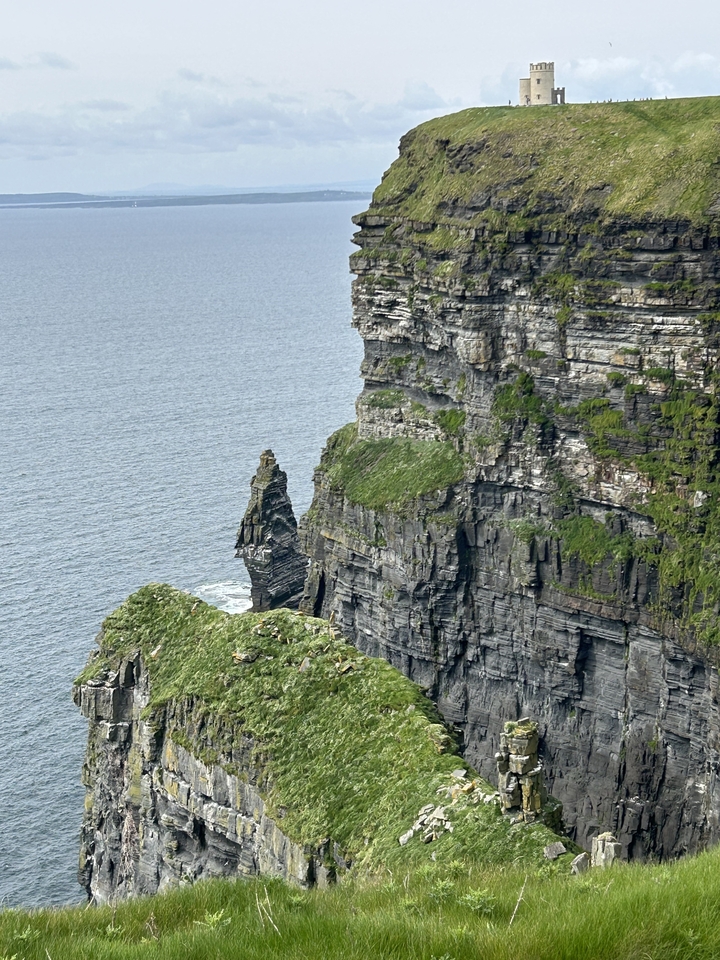 Gros plan des falaises de Moher avec l'océan en contrebas et de la verdure.