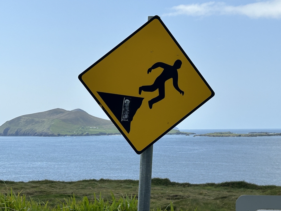 Un panneau d'avertissement représentant une personne tombant d'une falaise avec un océan en arrière-plan.