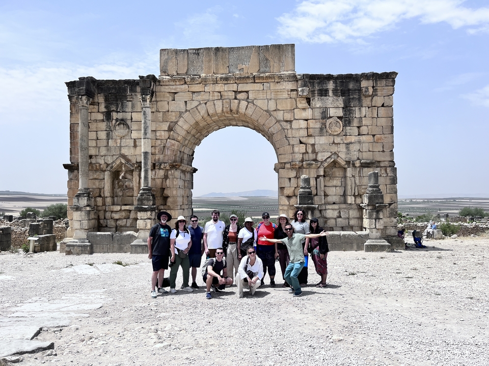 A group of people posing in front of an ancient archway.