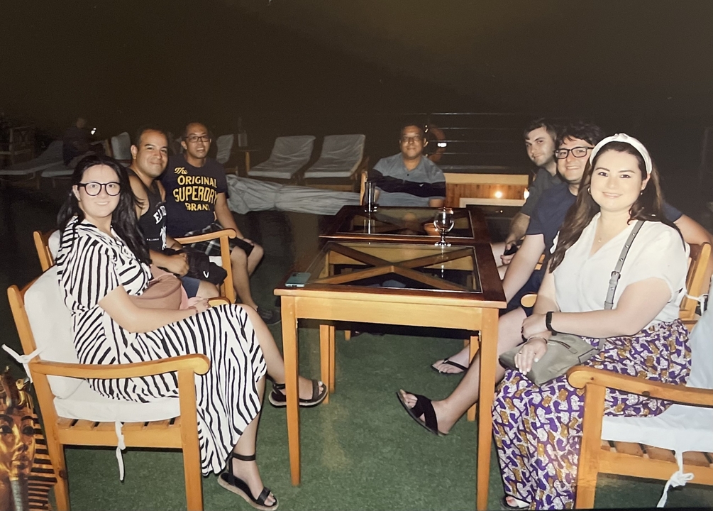 Groupe de personnes assises autour d'une table à l'extérieur la nuit.