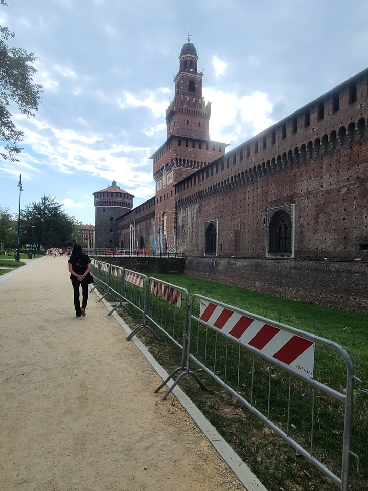 Person walking by an ancient castle wall.