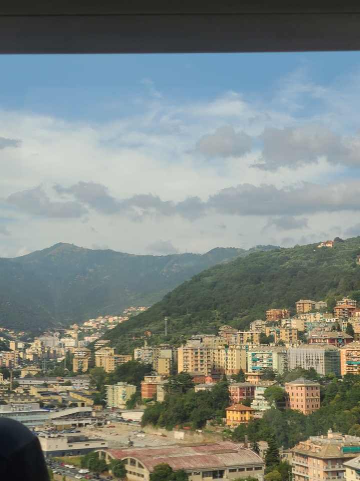 Hillside view with scattered houses and cloudy skies.