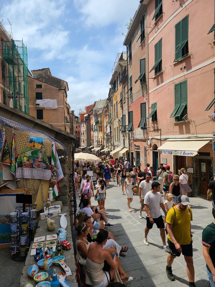 Crowded market street with shops and umbrellas.
