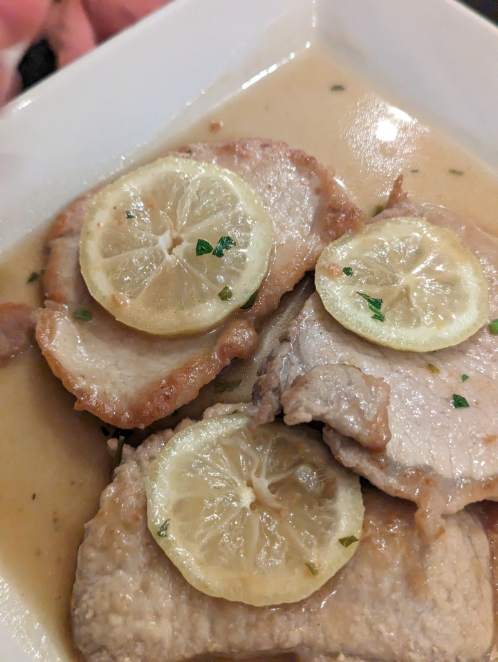 Close-up of a meat dish with lemon slices.