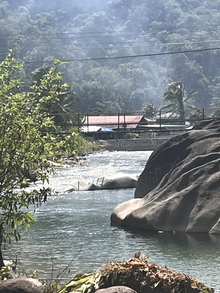 Une rivière avec un pont et un village en arrière-plan.