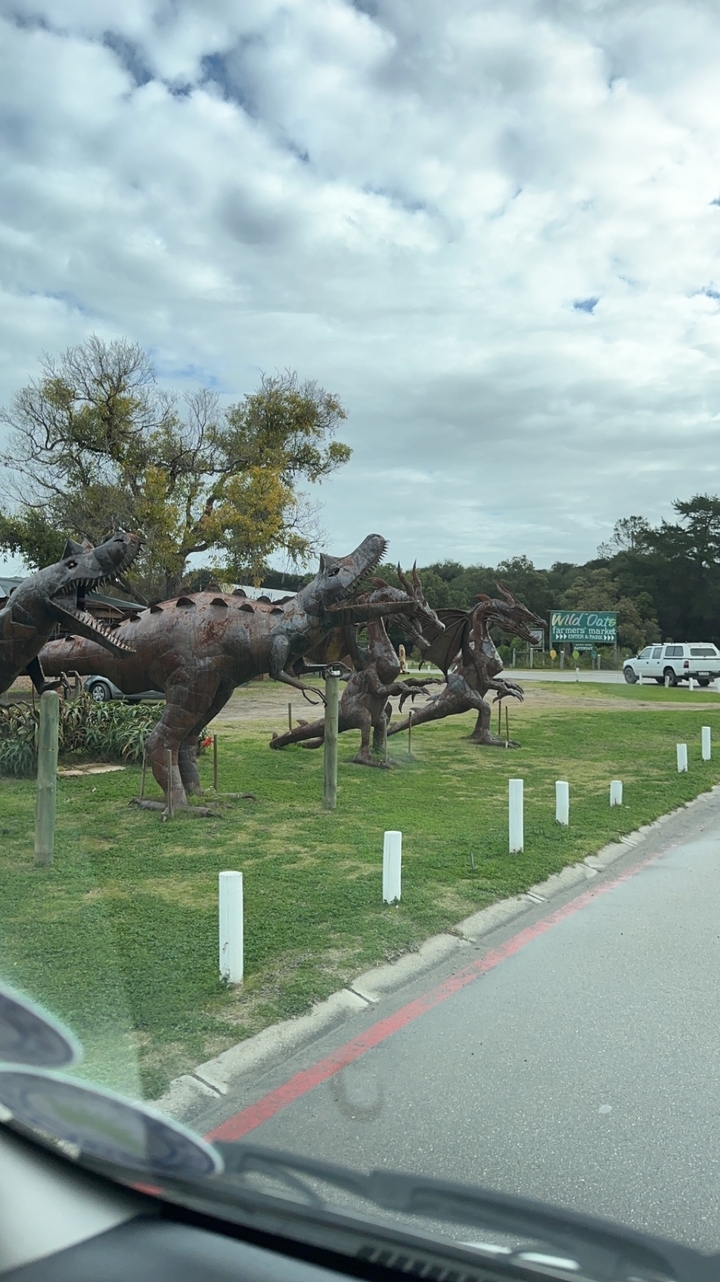 Metal dinosaur sculptures in a park setting.