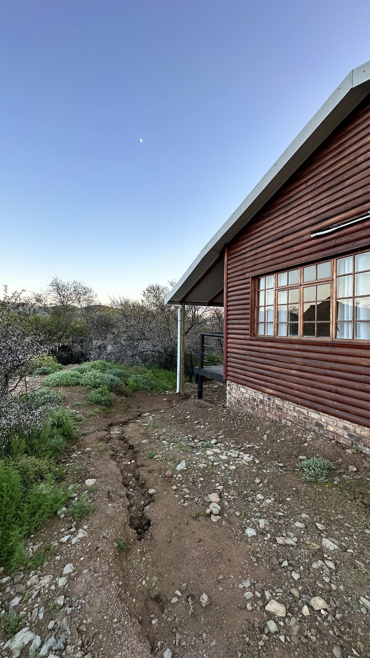 A wooden cabin in a natural setting with surrounding vegetation.